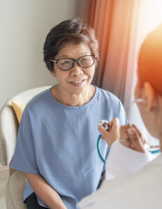 Older woman in hospital gown being examined by a doctor